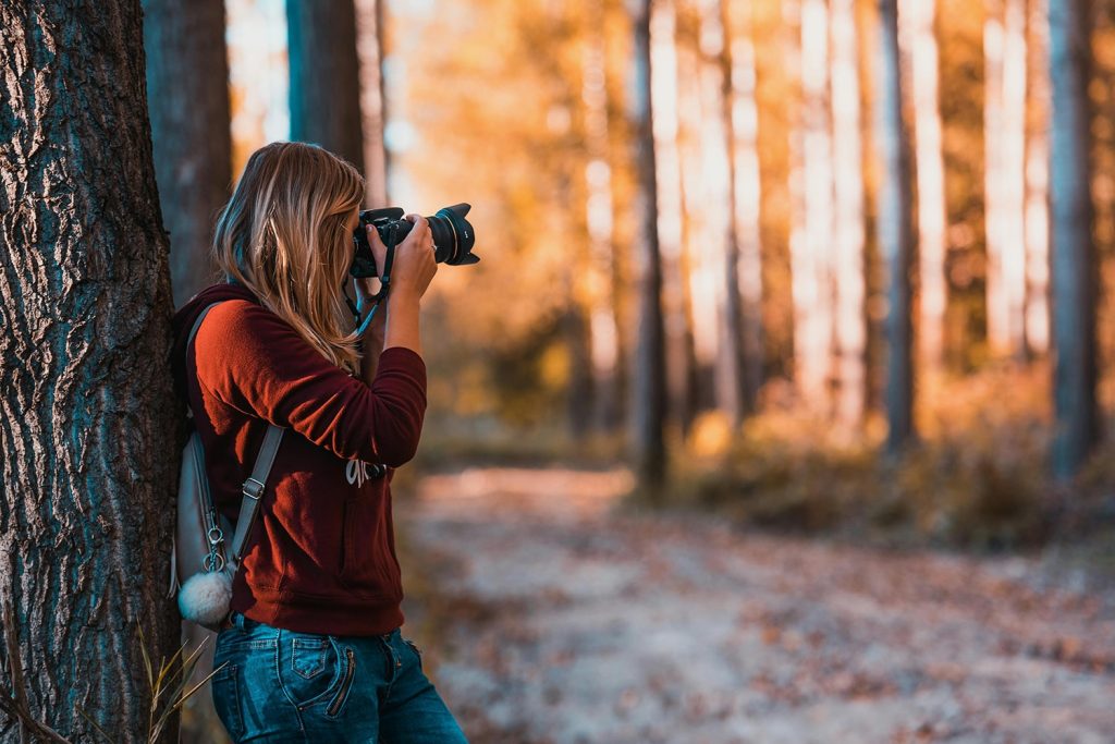 A woman in the forest doing photography, one of the alternative general hustles