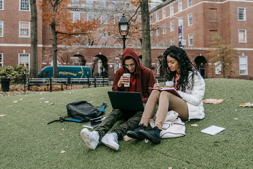 A man and woman on a laptop, in front of a small town building, one of the general hustles