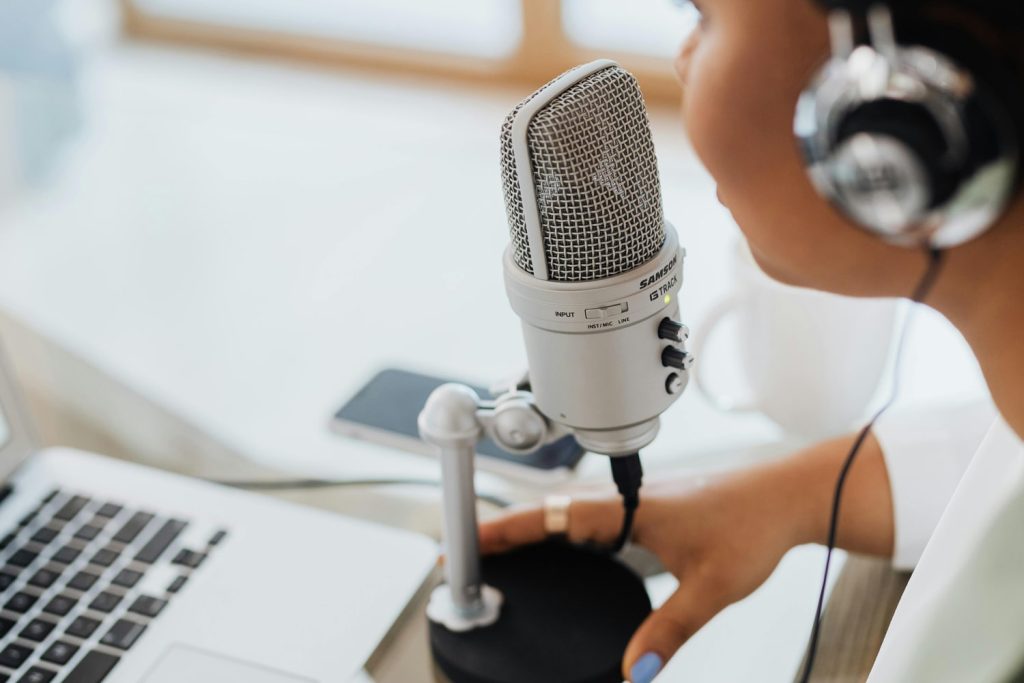 A woman talking into a microphone for a podcast, one of the online hustles