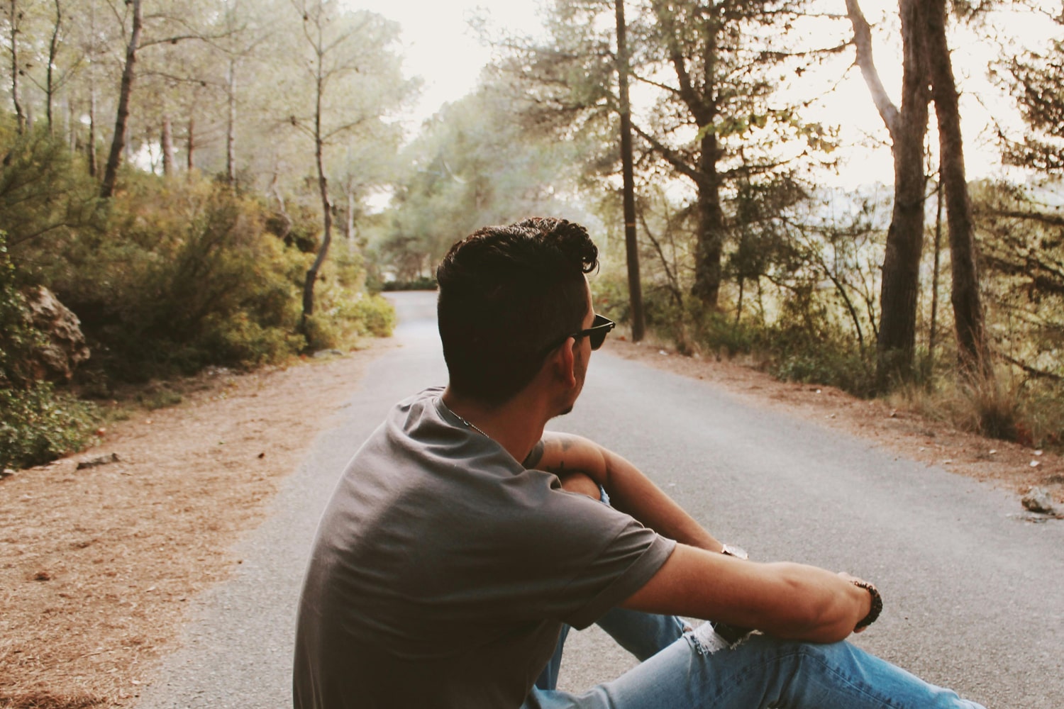 Young man sitting in the middle of the road, in a small town