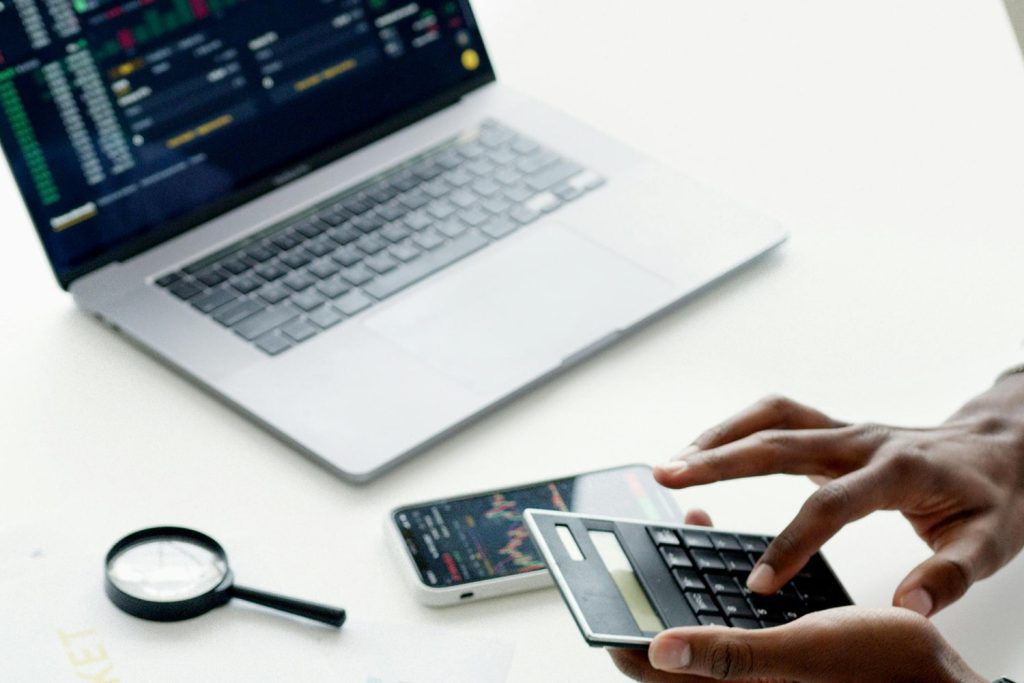 Man using his calculator, near a laptop and mobile phone