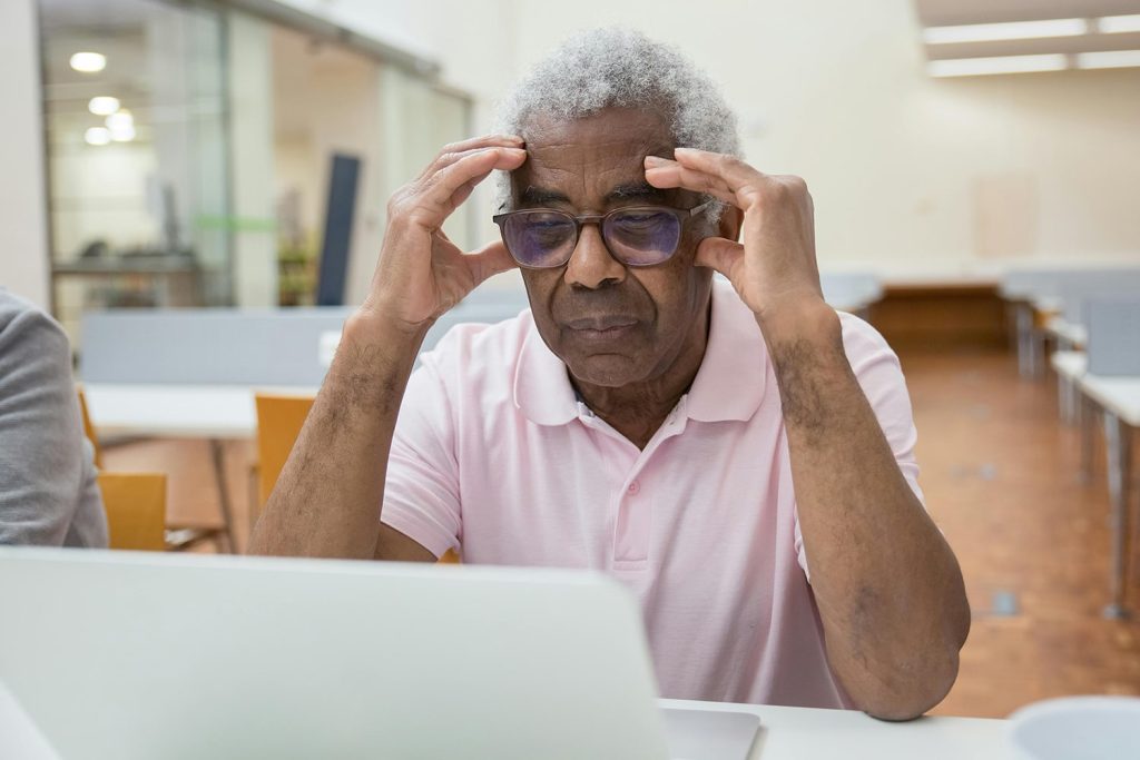 Older man struggling to read on laptop screen
