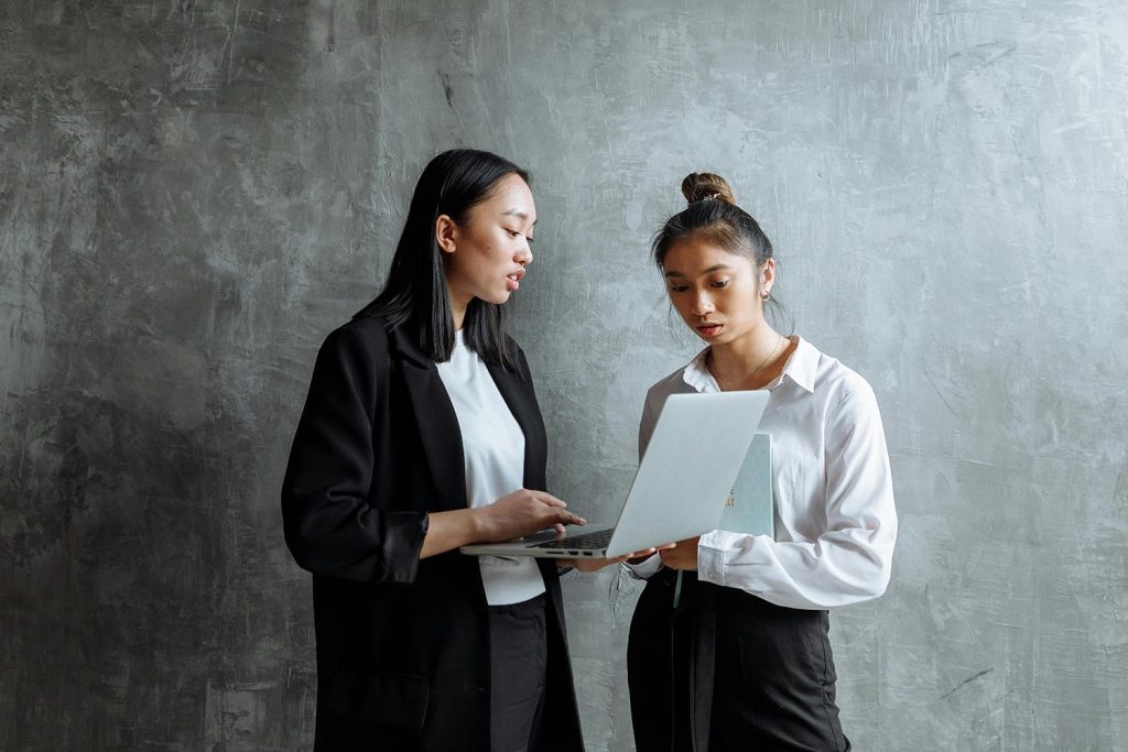 Two women talking near a black painted wall