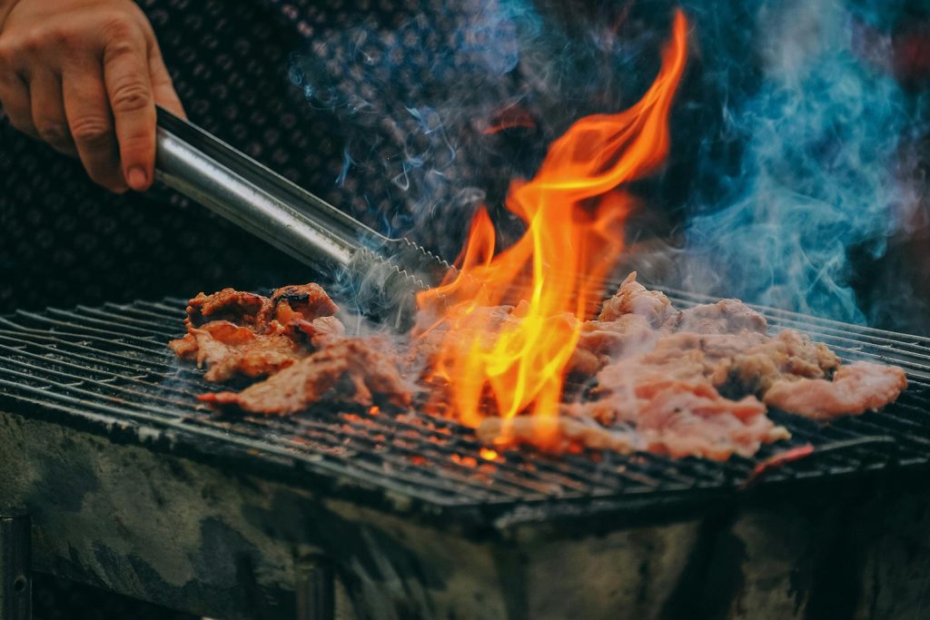 A view of someone cooking fresh BBQ meat on the grill