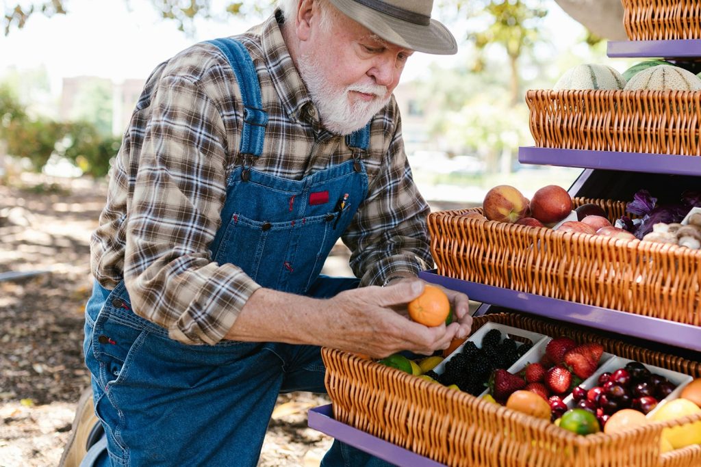 Older man outside looking at his fruits, his crops