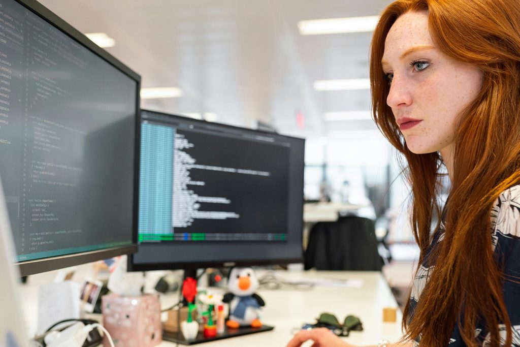 Woman looking at multiple screens, while on a laptop