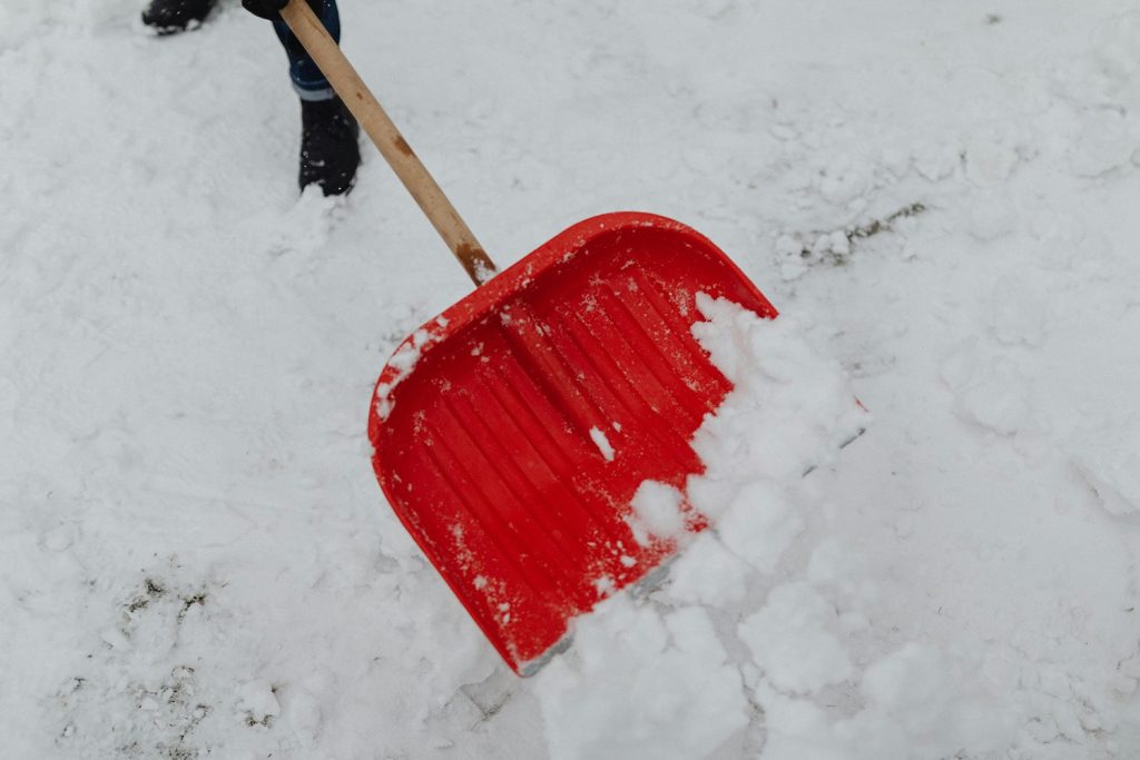 A red shovel picking up snow